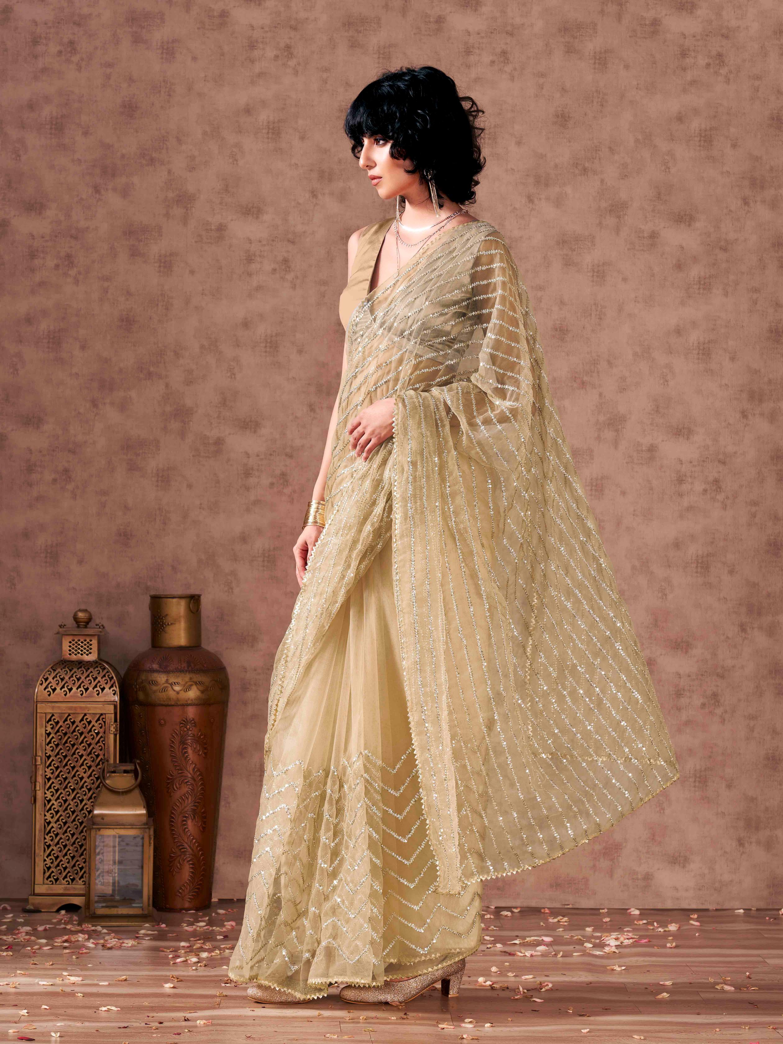 Beige colored sequinned embroidered net saree with embellished border