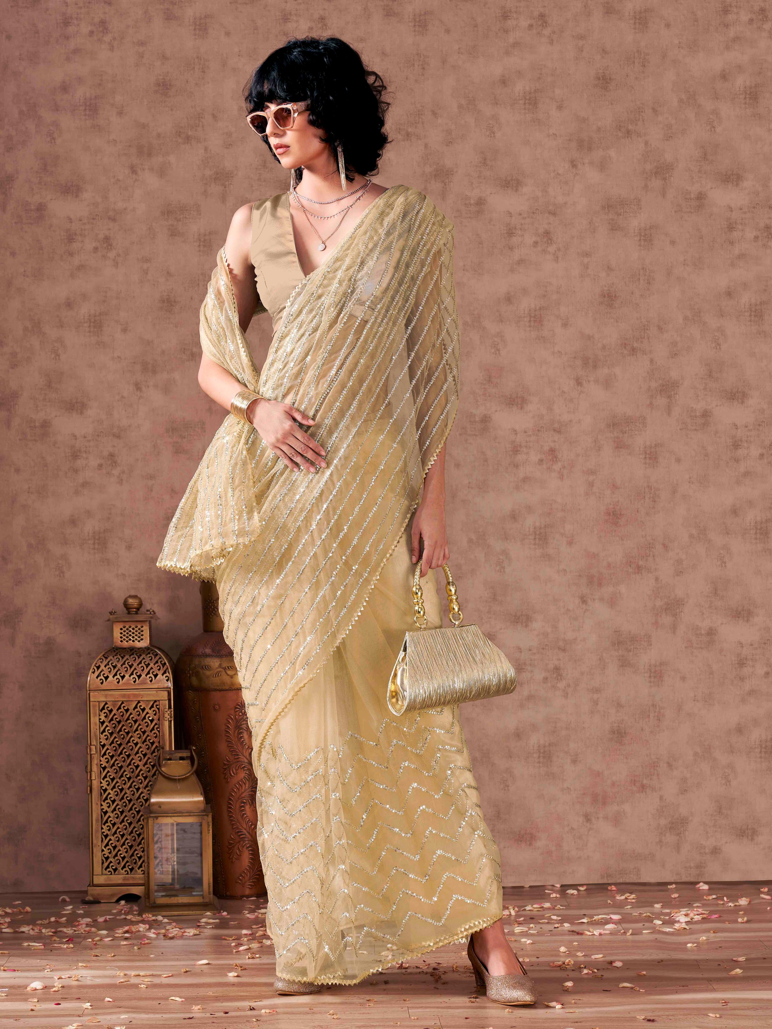 Beige colored sequinned embroidered net saree with embellished border