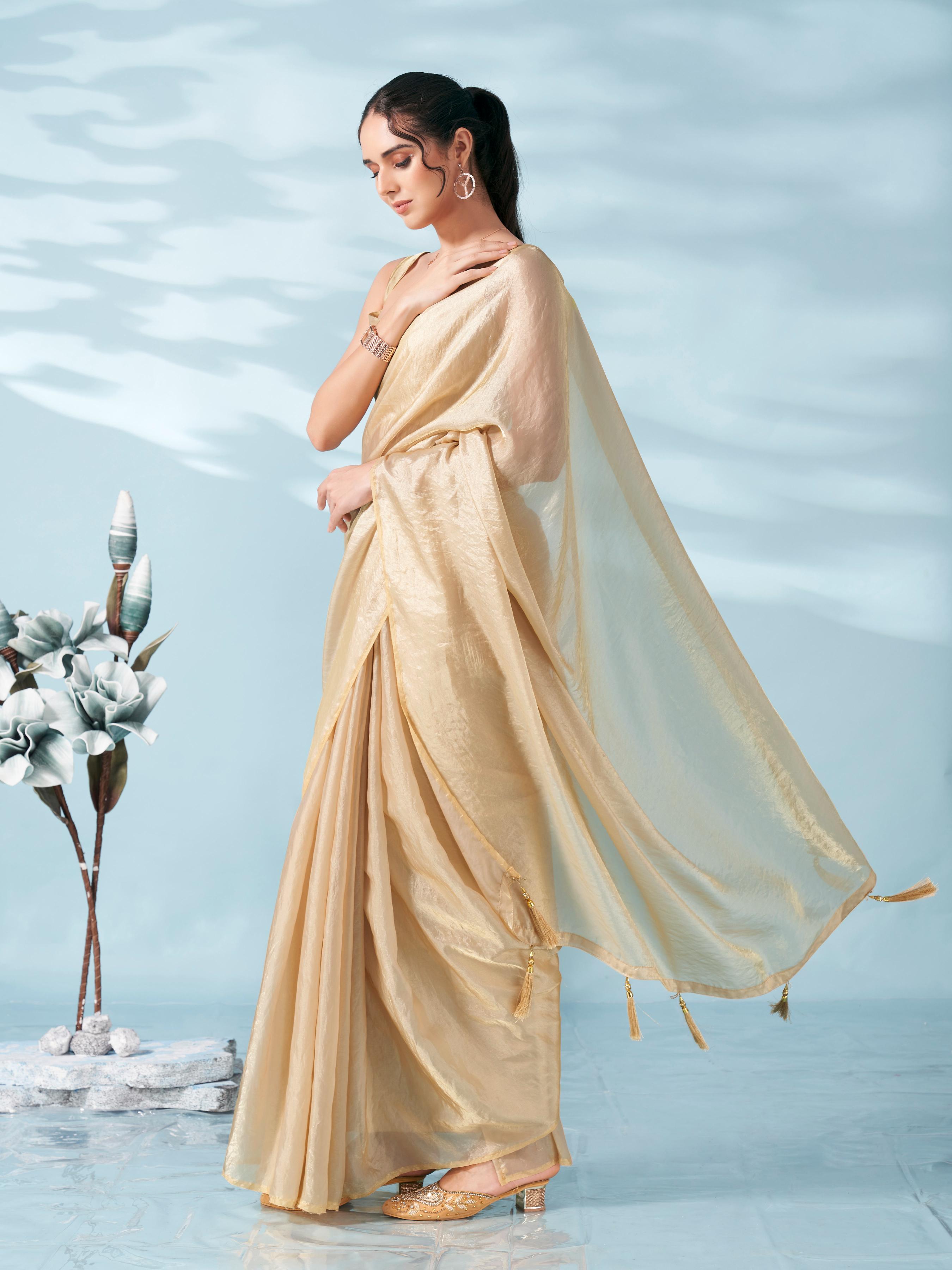 Beige colored satin saree with tassles on pallu