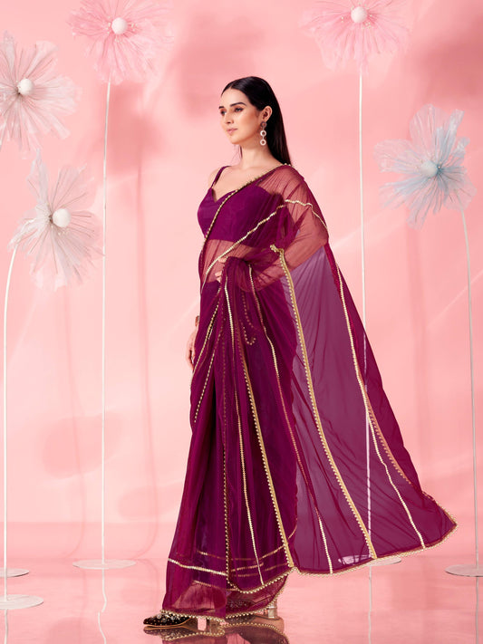 Violet colored designer net saree with faux beads and pearls stitched on pallu