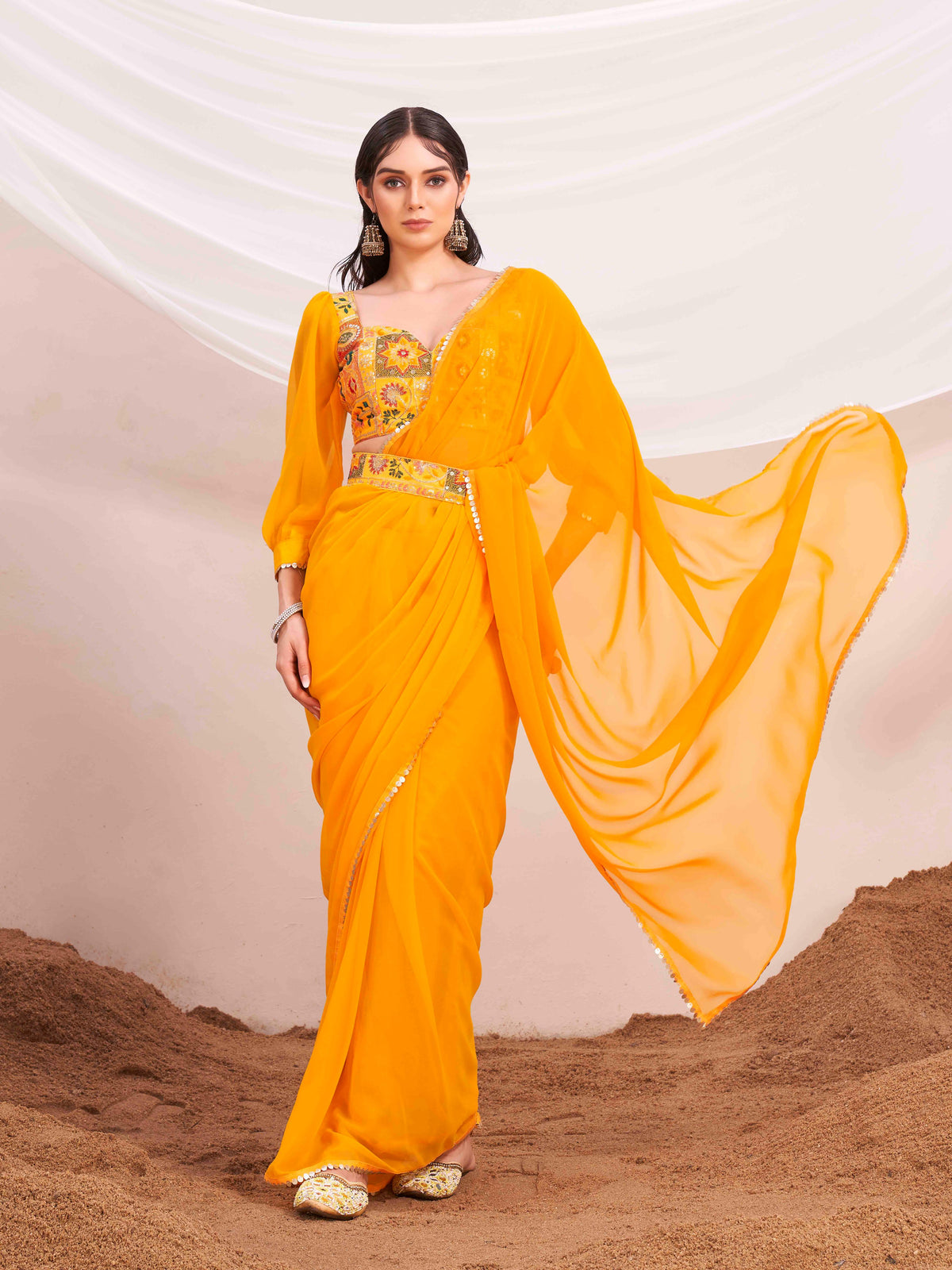 Yellow colored poly georgette saree with embroidered blouse and belt