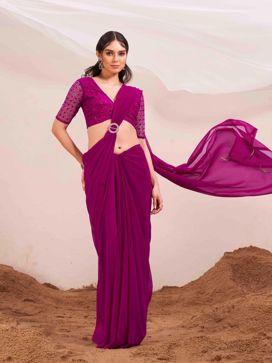 Pink colored designer poly georgette saree with embroidered blouse and a metallic ring on waist to accentuate the pallu