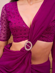 Pink colored designer poly georgette saree with embroidered blouse and a metallic ring on waist to accentuate the pallu